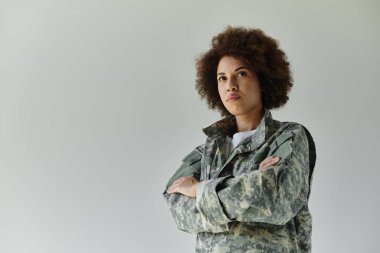 Kararlı genç bir Afrikalı Amerikalı asker gururla duruyor, kollarını kavuşturup, askeri ruhunu gösteriyor..
