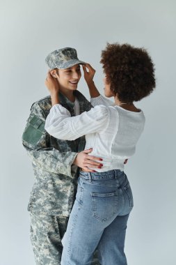 A loving farewell moment between a soldier and her wife in a warm studio atmosphere. clipart