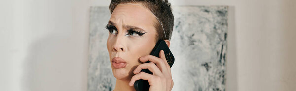 A stylish young drag queen poses thoughtfully while on the phone.