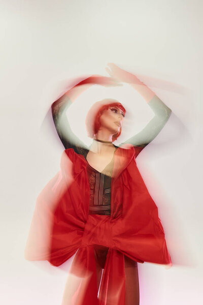 An attractive drag queen showcases style with flair in a striking red outfit.