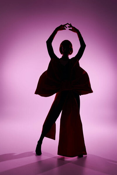 An attractive young drag queen showcases a bold pose in a striking silhouette.