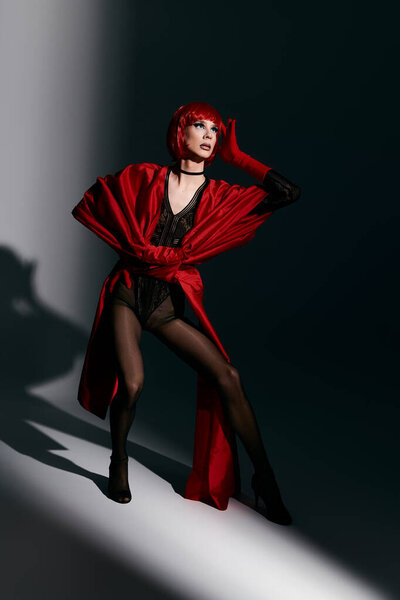 A captivating drag queen showcases a bold pose in vibrant red attire.