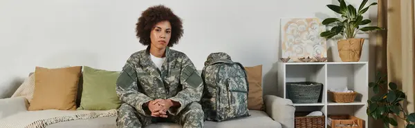 stock image A female soldier sits thoughtfully in her living room, ready to embark on her military journey.