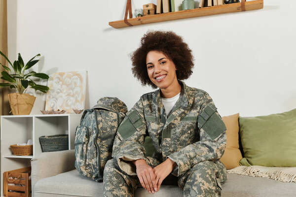 Молодая женщина в военной одежде удобно сидит в гостиной и готовится к предстоящей службе..