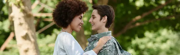 stock image A young soldier in camouflage is warmly welcomed by her smiling wife in a joyful reunion.