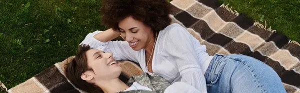 stock image A young soldier in camouflage is warmly welcomed by her wife, celebrating their joyful reunion outdoors.