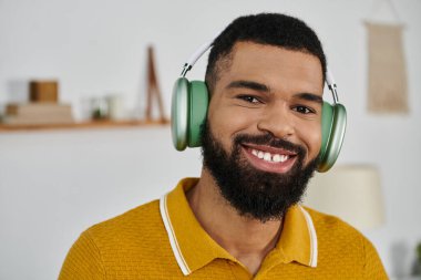 Neşeli bir adam evde rahatlar, kulaklıkla müziğin tadını çıkarır..