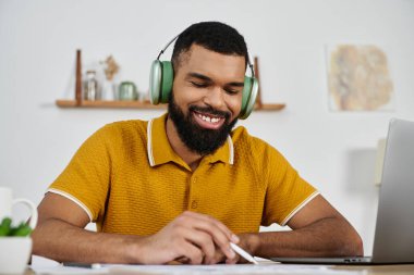 Bir adam evde bir proje üzerinde çalışırken gülümser, kendini müziğe ve görevlere verir..