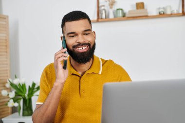 Gülümseyen bir adam evinde telefon görüşmesi yapar..