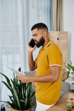 Rahat bir yaşam alanında bir adam telefonda kitap okurken meseleleri tartışır..