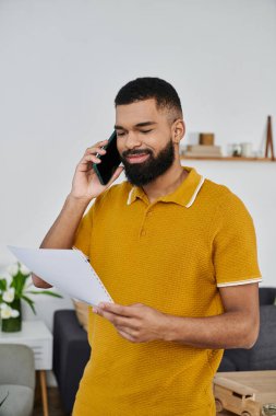 Adamın biri evde notları incelerken telefonla konuşuyor..