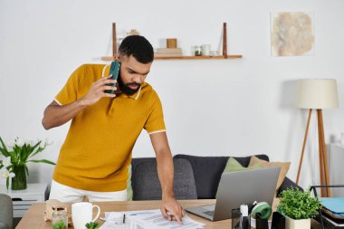 Bir adam, evindeki belgeleri incelerken telefonla iletişim kuruyor..