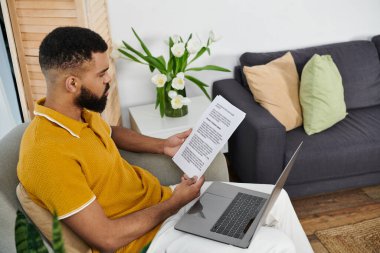 A man reviews important papers while sitting comfortably in his living space. clipart