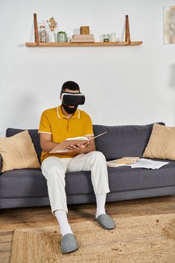 Relaxing at home, a man explores a virtual world with a book in hand. clipart