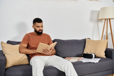 Yakışıklı bir adam evinde rahat bir kanepede sessizce kitap okumaktan hoşlanır..