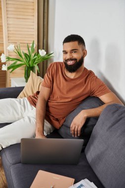 Şık bir adam laptopuyla rahatça uzanır, rahat bir öğleden sonra titreşimini kucaklar..