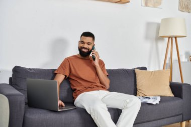 Bir adam evinde rahat rahat otururken telefonla konuşmaktan zevk alır..