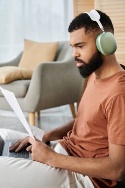 Odaklanmış adam, evde rahat otururken belgeleri gözden geçirir.