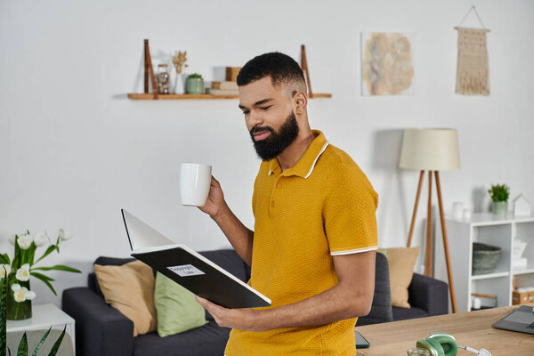 Мужчина расслабляется дома, потягивая кофе, читая книгу.