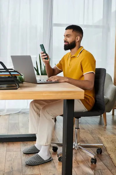 stock image A stylish man enjoys his leisure time at home with a phone and laptop.