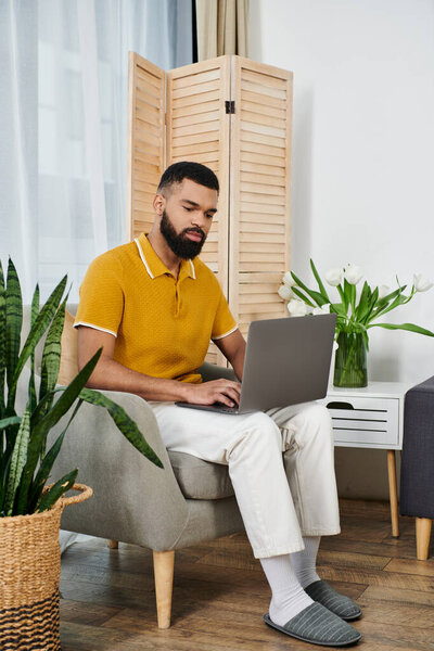 Стильный человек с ноутбуком в спокойной домашней обстановке.