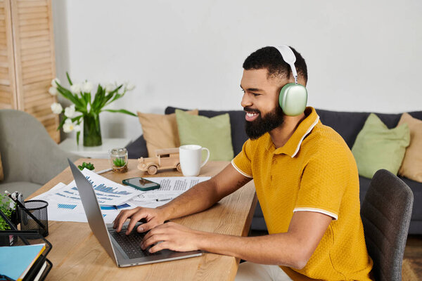 A smiling man engages with his laptop, surrounded by a cozy home atmosphere.