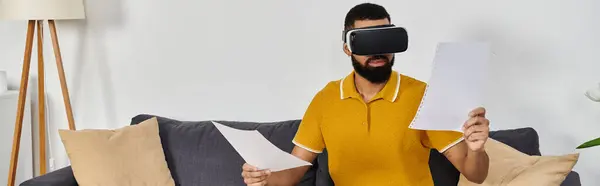 stock image A man explores a virtual reality world while seated comfortably at home.