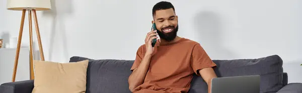 stock image A man enjoys a lively conversation while lounging comfortably at home.