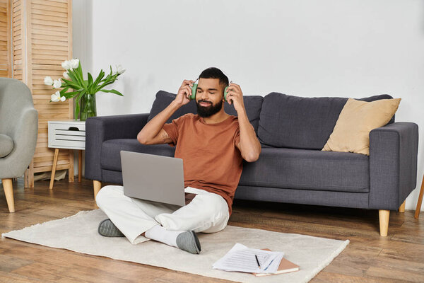 Мужчина дома расслабляется, слушая музыку на ноутбуке.