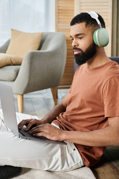 Расслабленный человек вовлекается в работу со своим ноутбуком в наушниках дома.