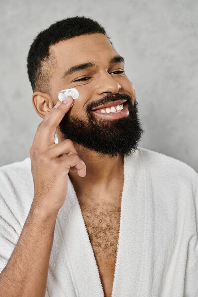 Расслабленный человек применяет кожу с радостным выражением лица дома.