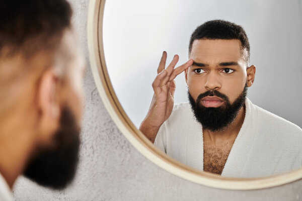 A man carefully applies grooming products while gazing in a mirror.