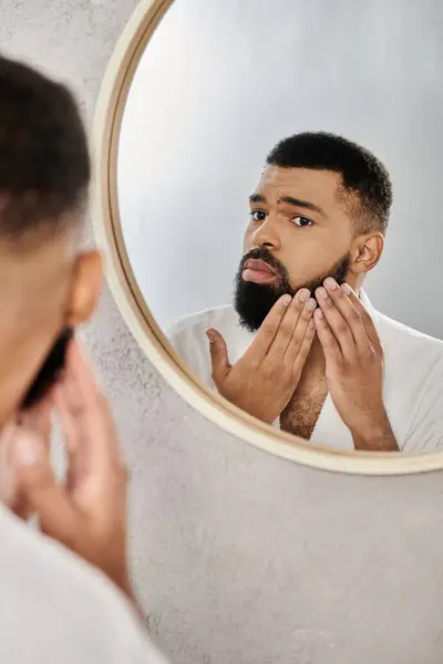 stock image Man carefully grooms his beard while admiring his reflection.