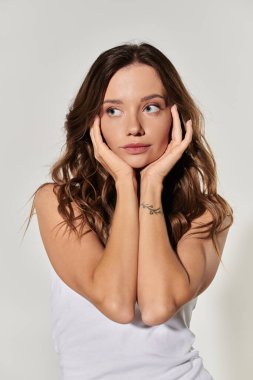 Zarif genç bir bayan düşünceli bir ifadeyle gündelik giysiler içinde poz verir..