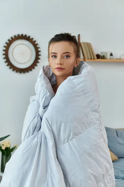 stock image A young woman enjoys the warmth of a blanket on a relaxing morning.