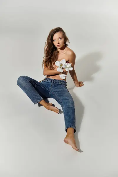 stock image Woman poses gracefully, holding flowers, showcasing a blend of beauty and confidence.