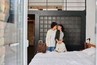 Mutlu bir çift, bavulları ve sıcaklığıyla çevrili otel odalarında hassas bir anı paylaşır..
