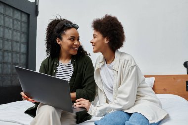 Mutlu bir çift, otel odasındaki dizüstü bilgisayarda gülüp, keşfe çıkarak samimi bir anı paylaşır..