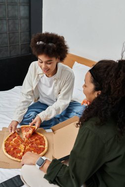 Mutlu bir çift gülüyor ve sıcak otel odalarında lezzetli bir pizzayı paylaşıyor..