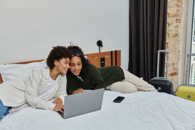 Mutlu bir çift otel odalarında bir dizüstü bilgisayarla seyahat seçeneklerini incelerken sakin bir anı paylaşıyor..