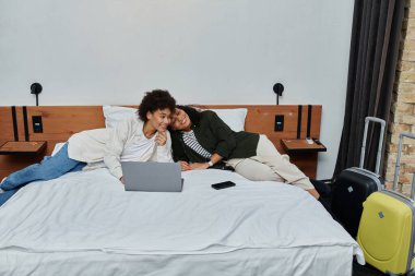 A happy couple relaxes and connects while enjoying their cozy hotel room adventure. clipart