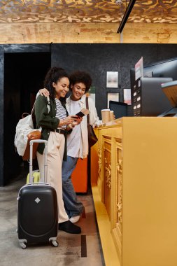 A joyful couple reviews their travel details while checking into a welcoming hostel. clipart