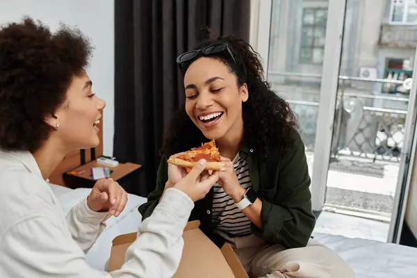 stock image A happy couple shares a moment of joy as they savor pizza in their cozy hotel room.