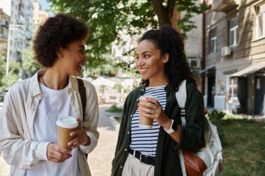 A joyful couple shares coffee and laughter while exploring a vibrant outdoor setting together.