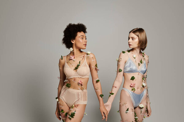 Two women share a tender connection, adorned with delicate flowers.