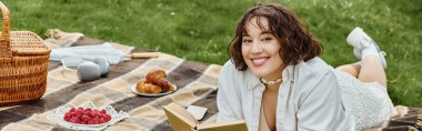 A young woman in a white shirt relaxes on a picnic blanket, savoring summer and a good book. clipart