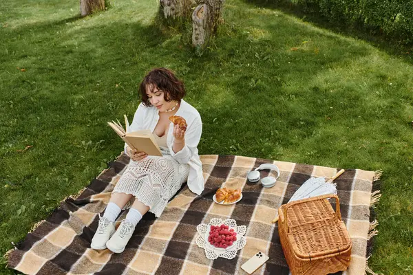 Güneşli bir öğleden sonra, çimenlerin üzerinde bir battaniyeye oturmuş, atıştırmalıkların ve güzel bir kitabın tadını çıkaran bir kadın bulur..