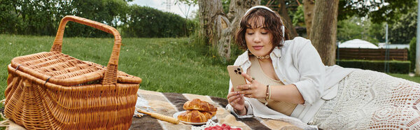 A young woman lounges in a white shirt, enjoying a sunny day at a picturesque summer picnic.