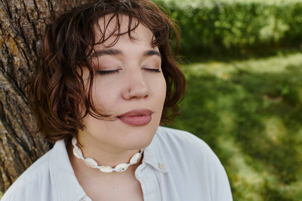 A young woman enjoys the warmth of summer, immersed in the tranquility of a green park.