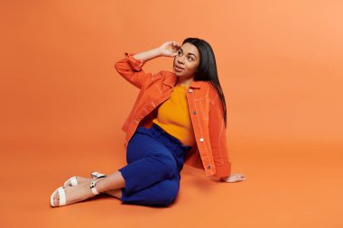 Kendine güvenen bir kadın, moda anlayışını parlak bir arkaplanda sergiliyor..